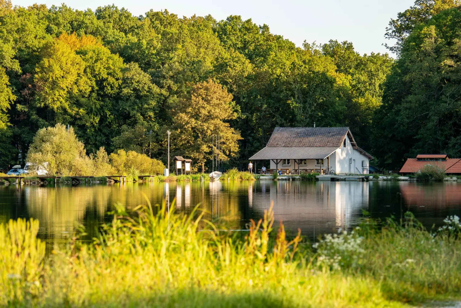 See mit Haus im Wald im Abendlicht